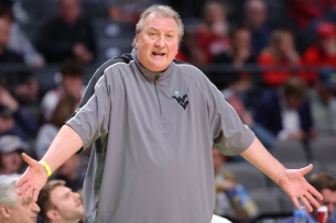 A man in a gray track suit on a basketball court