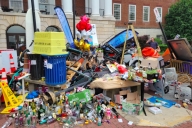 A colorful array of trash, bottles, stolen signs, electric scooters, trash cans, a lamppost and more are scattered around a statue of the University of Maryland's terrapin mascot.